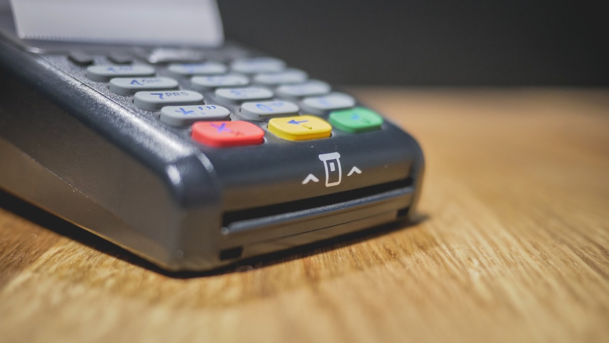Ancien terminal de paiement posé sur un comptoir en bois. Vue de profil.