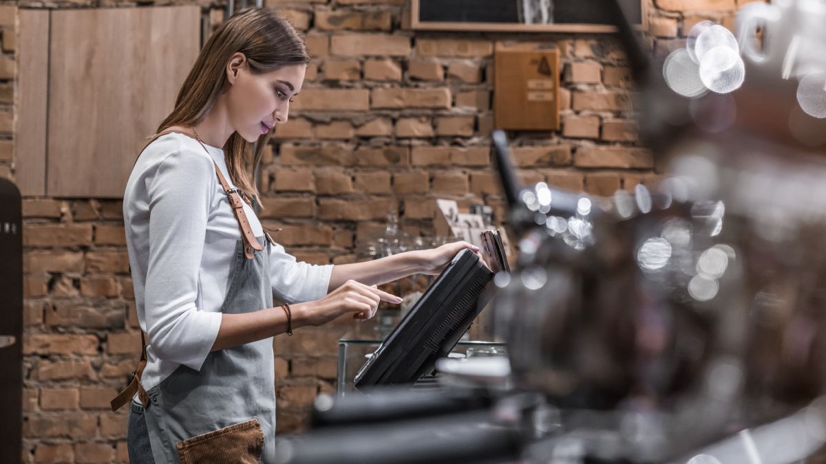 Une restauratrice utilisant une caisse enregistreuse tactile dans un restaurant.