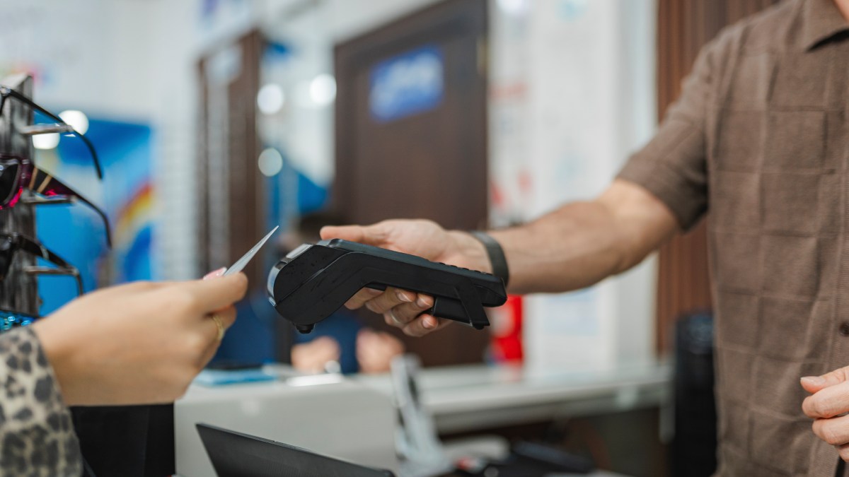Cliente qui paie sur un terminal mobile Bancontact avec sa carte de crédit.