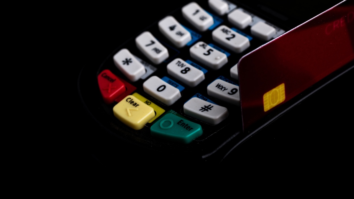 Terminal de paiement noir vu de près avec une carte de crédit sur la droite.