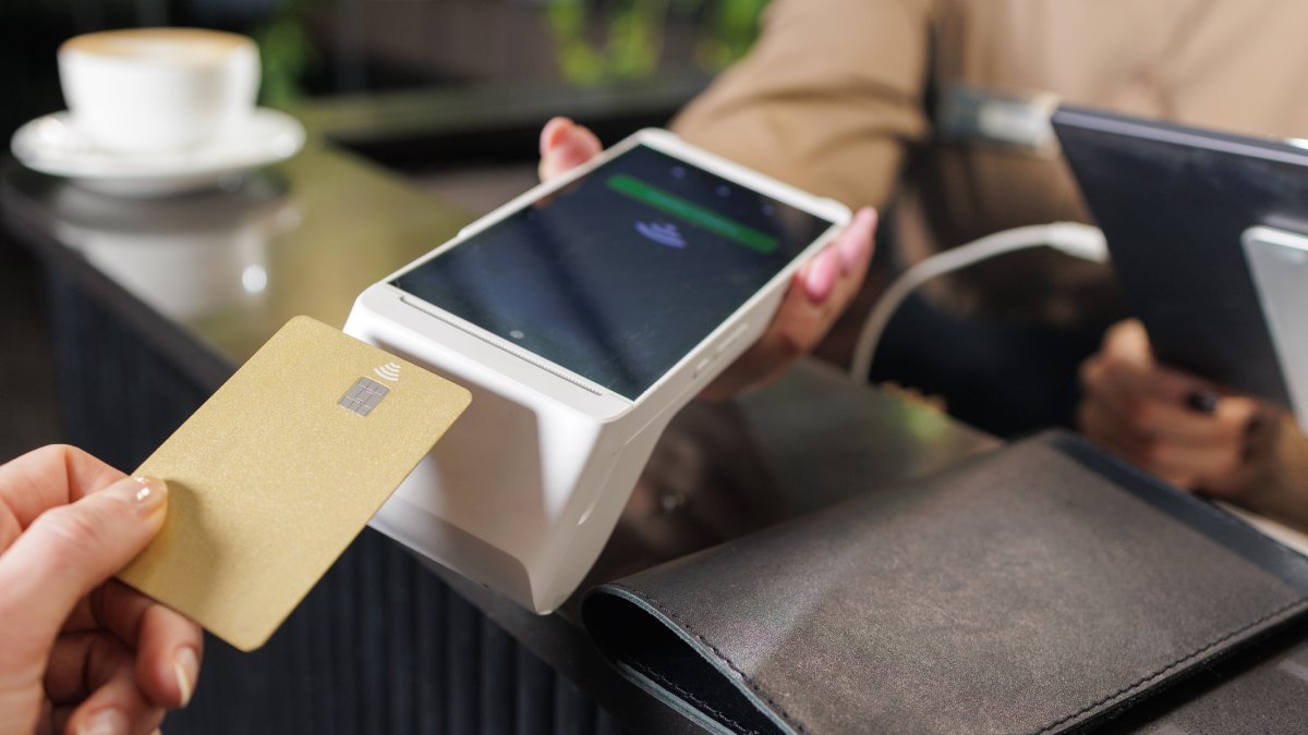 Paiement sans contact sur un terminal de paiement mobile de couleur blanche dans un café.