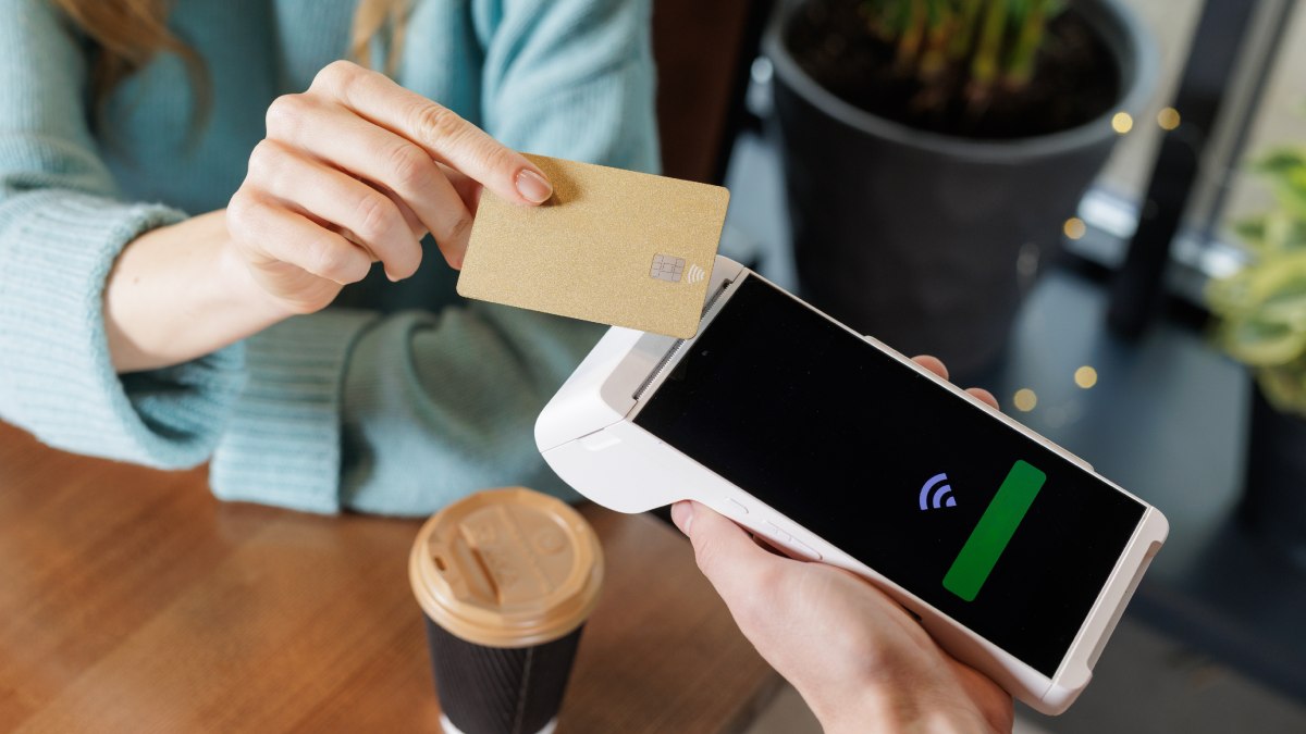 Cliente payant sur un terminal de paiement mobile avec sa carte de crédit et sans contact.