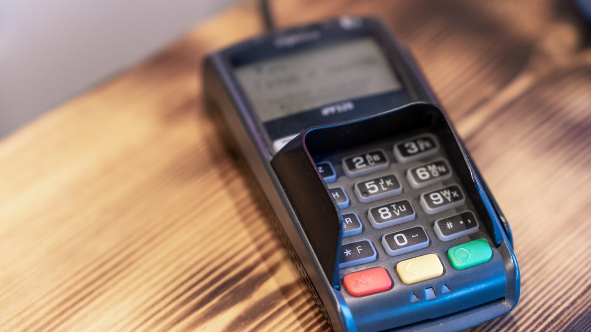 Terminal de paiement fixe branché sur le comptoir en bois d'un magasin.