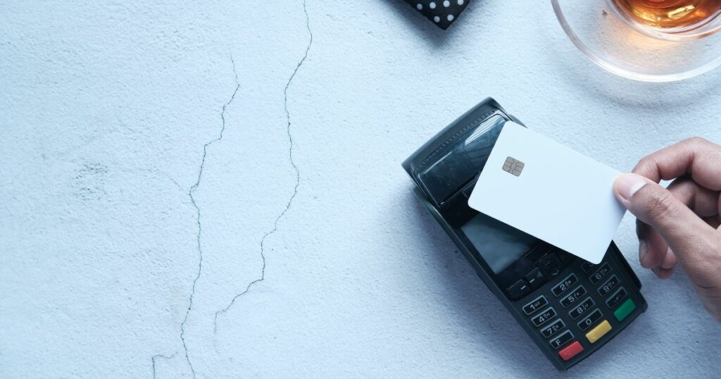 terminal de paiement sur une table en marbre blanc avec une main en train de poser sa carte bancaise dessus pour effectuer un paiement sans contact