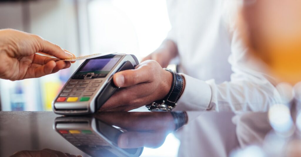paiement electronique effectué par un serveur en chemise blanche et un client qui paie à l'aide d'une carte de crédit