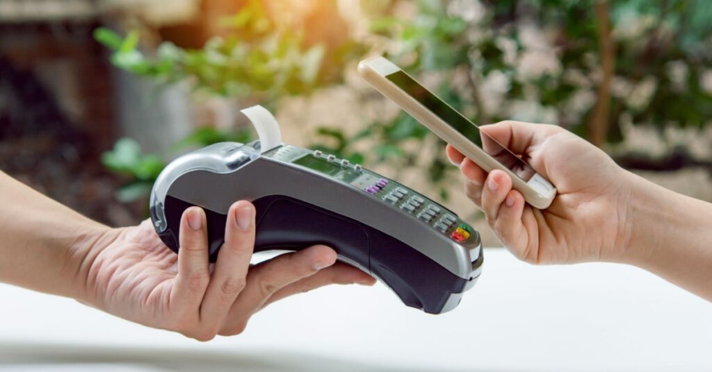 terminaux de paiement mobiles tenus par la main d'une serveuse avec une cliente en train de régler la note directement à sa table